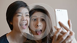 Two happy photogenic Asian womans talking selfie with phone