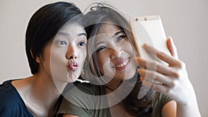 Two happy photogenic Asian womans talking selfie with phone