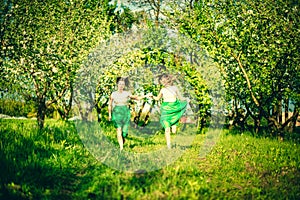 Two happy pretty girls walking on the apple trees garden