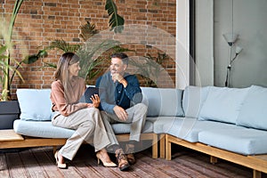 Two happy professional business executives talking using tablet in office.