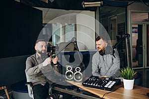 Two happy radio presenters having a good time on air. Young men smiling happily while recording an audio broadcast in a