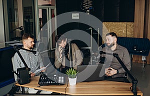 Two happy radio presenters having a good time on air. Young men smiling happily while recording an audio broadcast in a