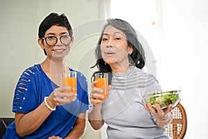 Two happy retired middle-aged Asian women sitting in a dining room