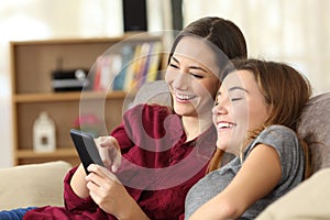 Two happy roommates checking smart phone content at home photo