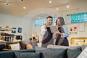 two happy shop clerks as if celebrating something while using a tablet