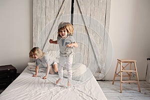 Two happy sibling boys playing together at home on bed