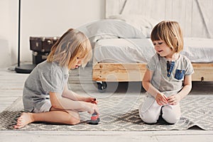 Two happy sibling boys playing together at home with toy cars