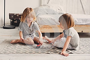 Two happy sibling boys playing together at home with toy cars