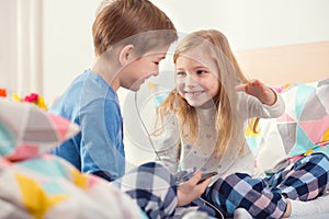 Two happy siblings children having fun and listening music with