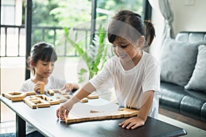 Two happy siblings playing a game with wooden blocks at home joyfully