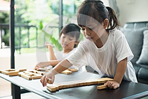 Two happy siblings playing a game with wooden blocks at home joyfully