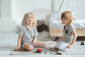 Two happy siblings playing with toy cars at home in the morning