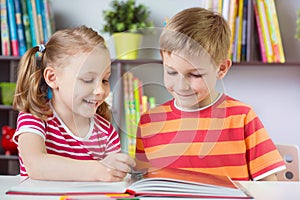 Two happy siblings reading interesting book