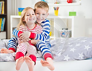 Two happy siblings in sleepwears in bed