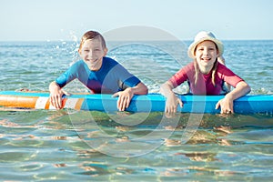 Two happy siblings teen children in neoprene suits having fun  with sup board in Baltic sea