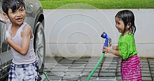 Two happy siblings washing car