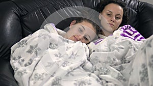 Two happy sisters lying on sofa in pijamas