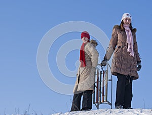 Two happy sisters sledding
