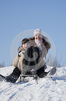 Two happy sisters sledding