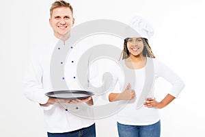 Two happy smile chefs holding an empty tray and show like sign isolated on white. White and afro american cookers in uniform