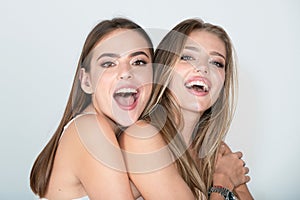 Two happy smiling girl friends blond and brunette on white background. Closeup face portrait of two young beautiful