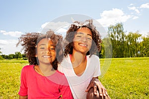 Two happy smiling girls in park lawn portrait