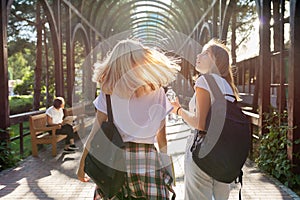 Two happy smiling talking girls teenagers students walking together