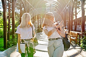 Two happy smiling talking girls teenagers students walking together