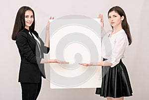 Two happy smiling young business women carrying big blank signbo