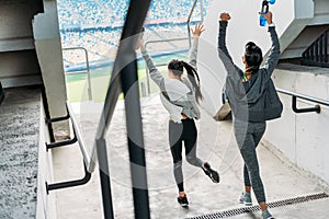 Two happy sportswomen in sportswear running to the stadium