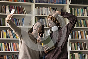 Two happy students make selfie in library