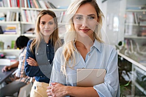 Two happy successful business female collegues standing next to each other in an office