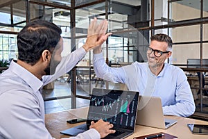 Two happy successful diverse traders investors giving high five.