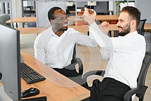 Two happy successful excited diverse traders investors giving high five celebrating successful stock exchange trading