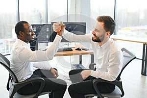 Two happy successful excited diverse traders investors giving high five celebrating successful stock exchange trading