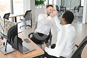 Two happy successful excited diverse traders investors giving high five celebrating successful stock exchange trading