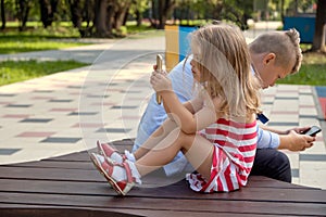 Two happy teenage friends using on mobile phone while relaxing in the park. Problems of modern youth, social networks