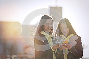 Two happy teenage girls friends using on mobile phone