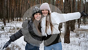 Two happy teenage girls laughing and cheering because of the first snow. People playing outdoors, winter holidays and vacation,