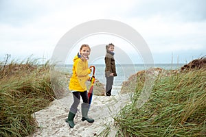 Two happy teenager siblings staing with ambrella on coast of Baltic sea at windy weather photo