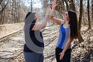 Two happy women friends give a five after jogging. Friendship, g