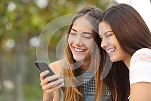 Two happy women friends sharing a smart phone
