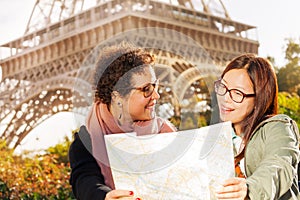 Two happy women with a paper tourist map in Paris