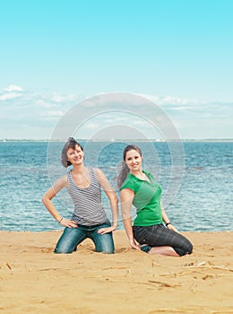 Two happy women sitting on the beach