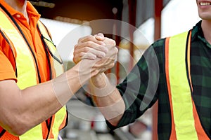 Two happy worker engineers with safety vest and helmet have strong handshake to greeting at construction building site. Architect