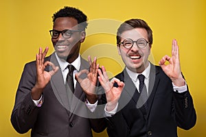 Two happy young african and caucasian businessmen showing OK sign photo