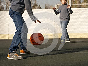 Two happy young boys playing basketball outdoors on a sports field