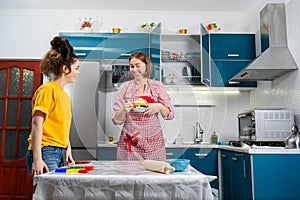 Two happy young Caucasian women cook together in the kitchen. The concept of LGBT couples and family cooking