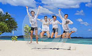 Two happy young couples jump on tropical white beach