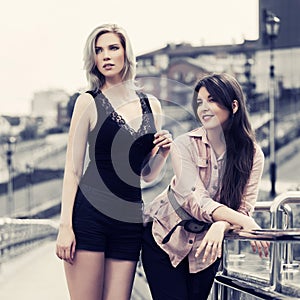 Two happy young fashion women on city street